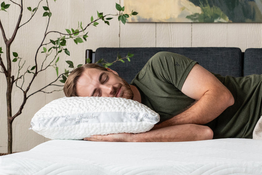 A man smiling while laying on his side on an easy breather side sleeper pillow