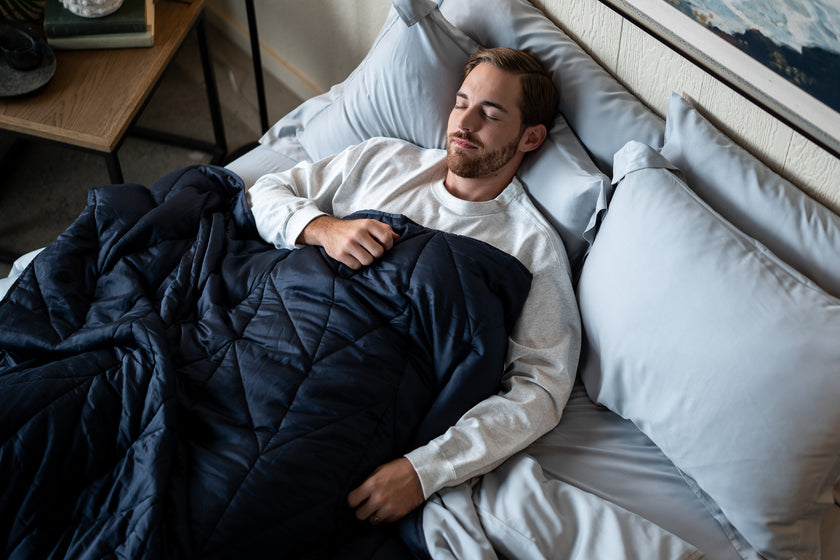 A man resting comfortably covered by a nest bedding luxury weighted blanket